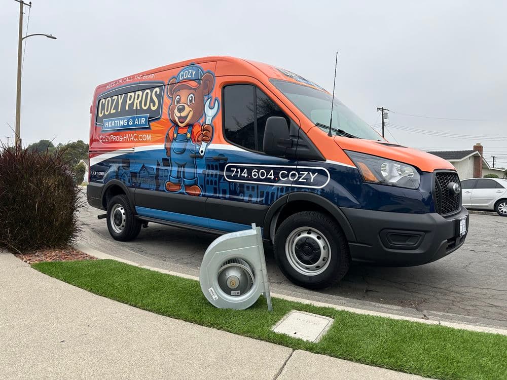 Cozy Pros Heating & Air van with bear mascot, parked on a street with mechanical equipment nearby.